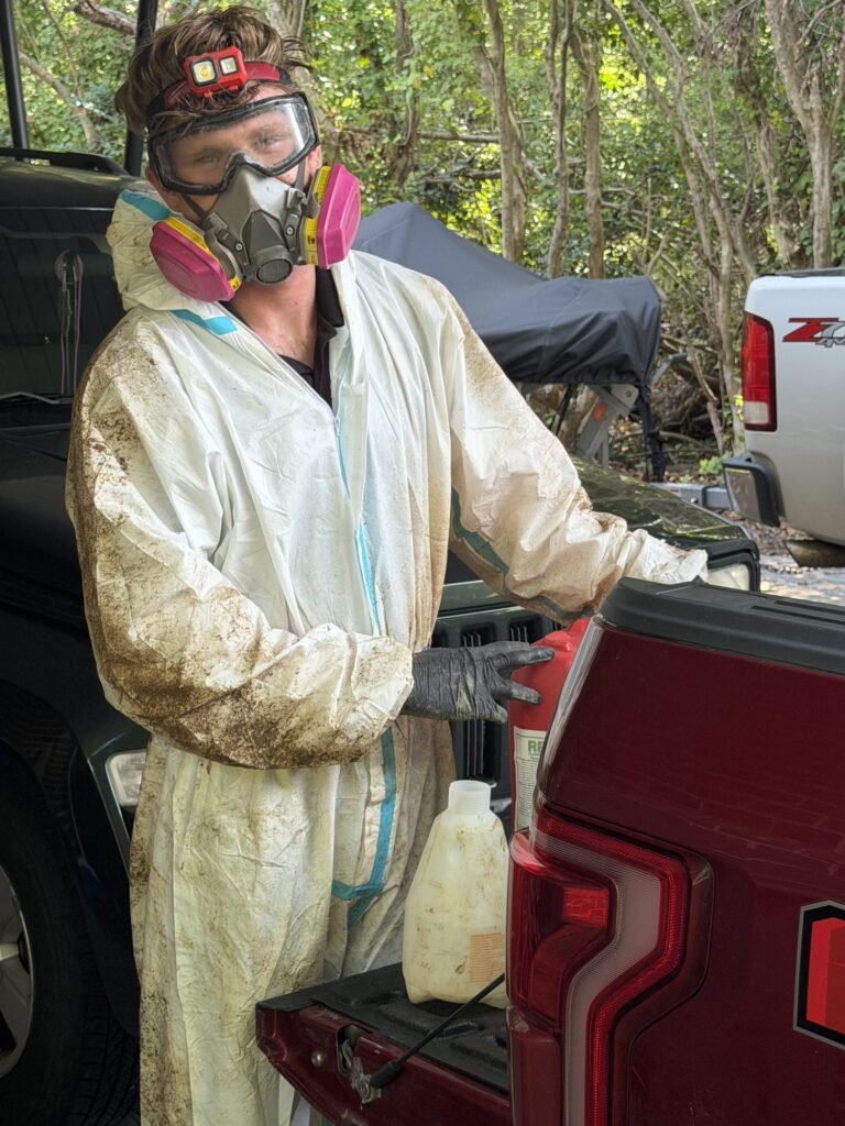 GreenShield crew member in protective suit and respirator after crawlspace work