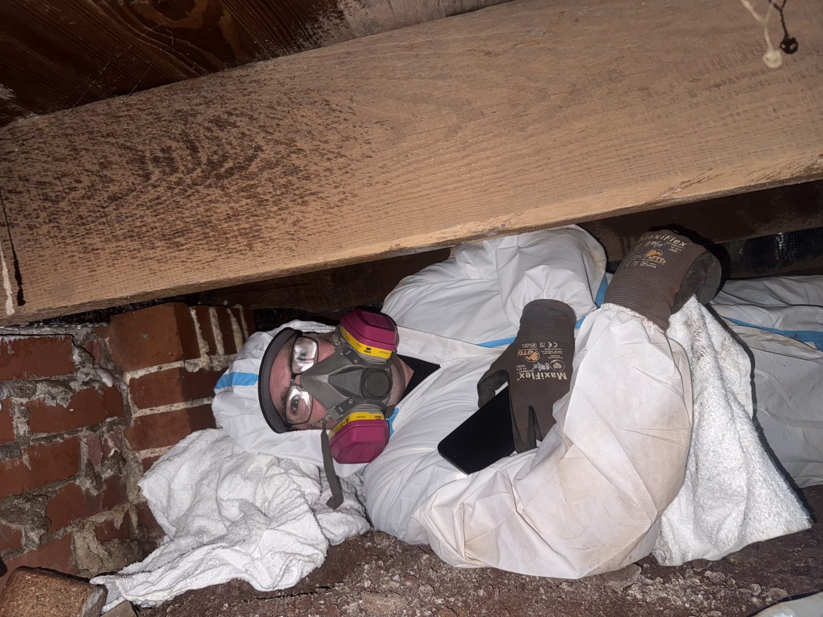 GreenShield Restoration technician in full PPE working inside a crawlspace