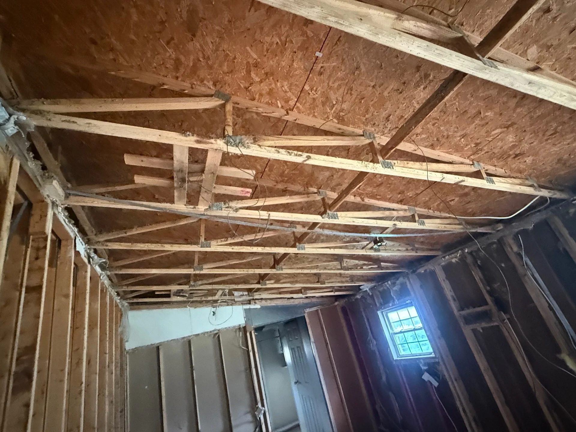 Exposed ceiling framing and wall studs during property damage reconstruction