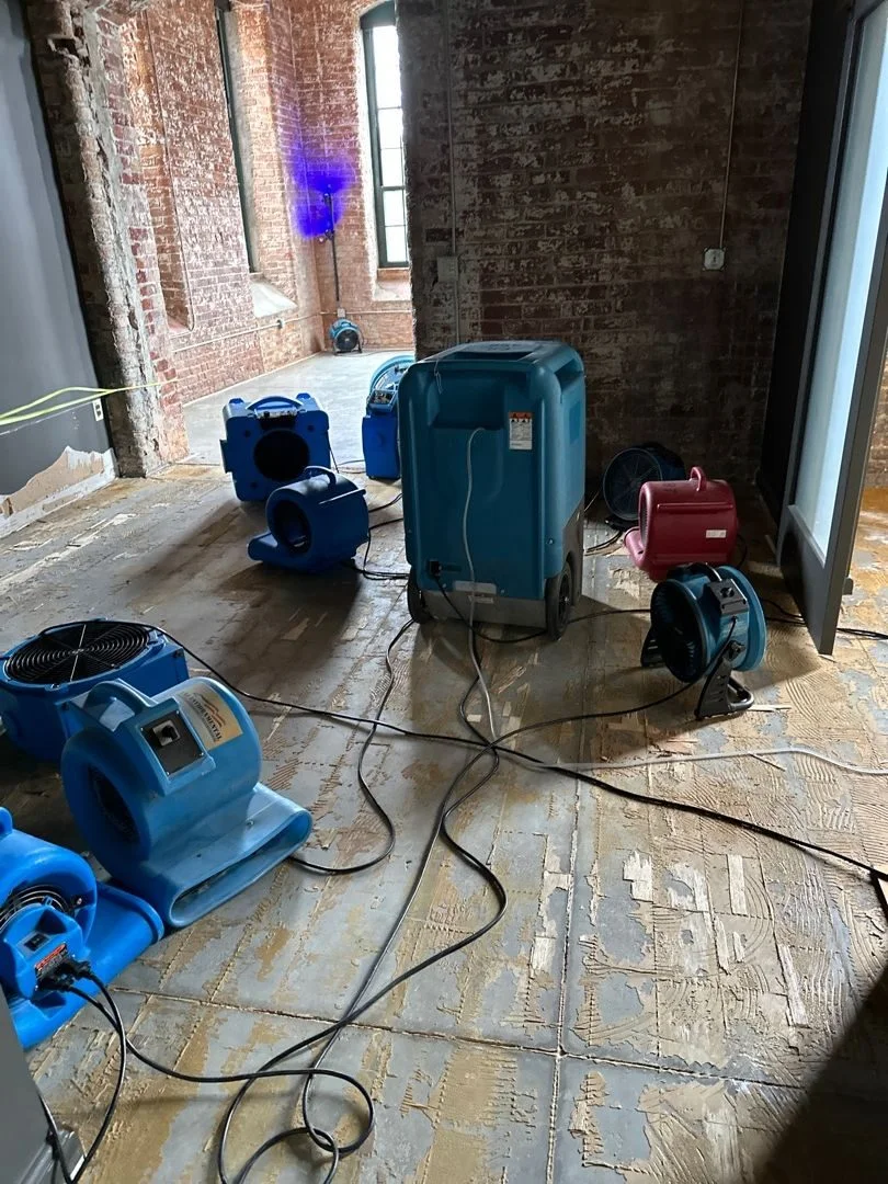 Commercial dehumidifiers and air movers drying a water damaged building